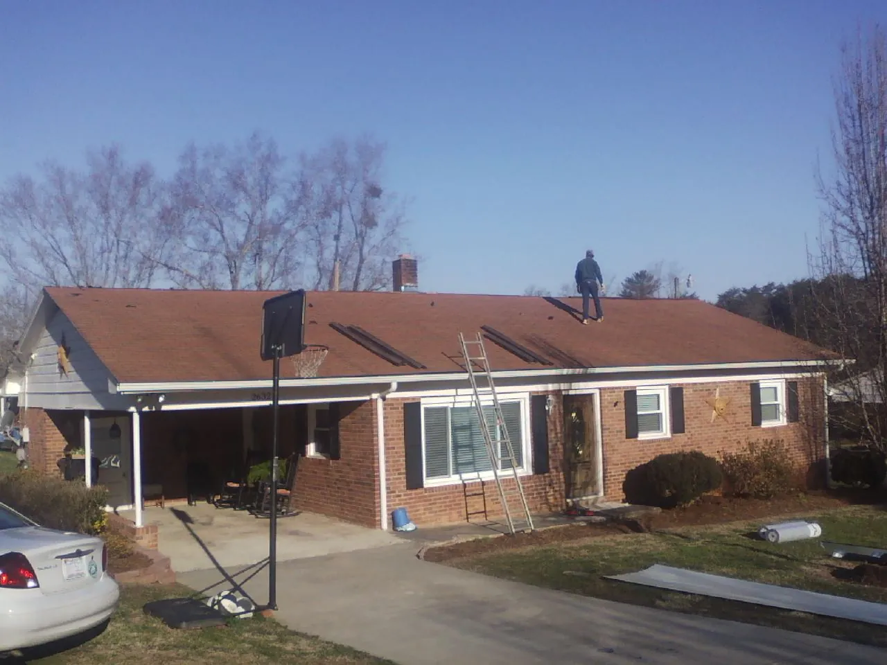 Roofer stripping a shingle roof on a brick ranch before metal panels in Franklin Furnace