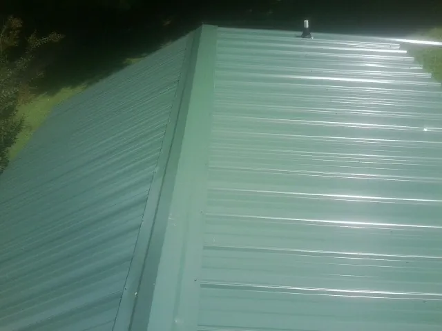 New green metal panels meeting at the ridge of a roof — Flat Roof Repair work by our crew in Franklin Furnace