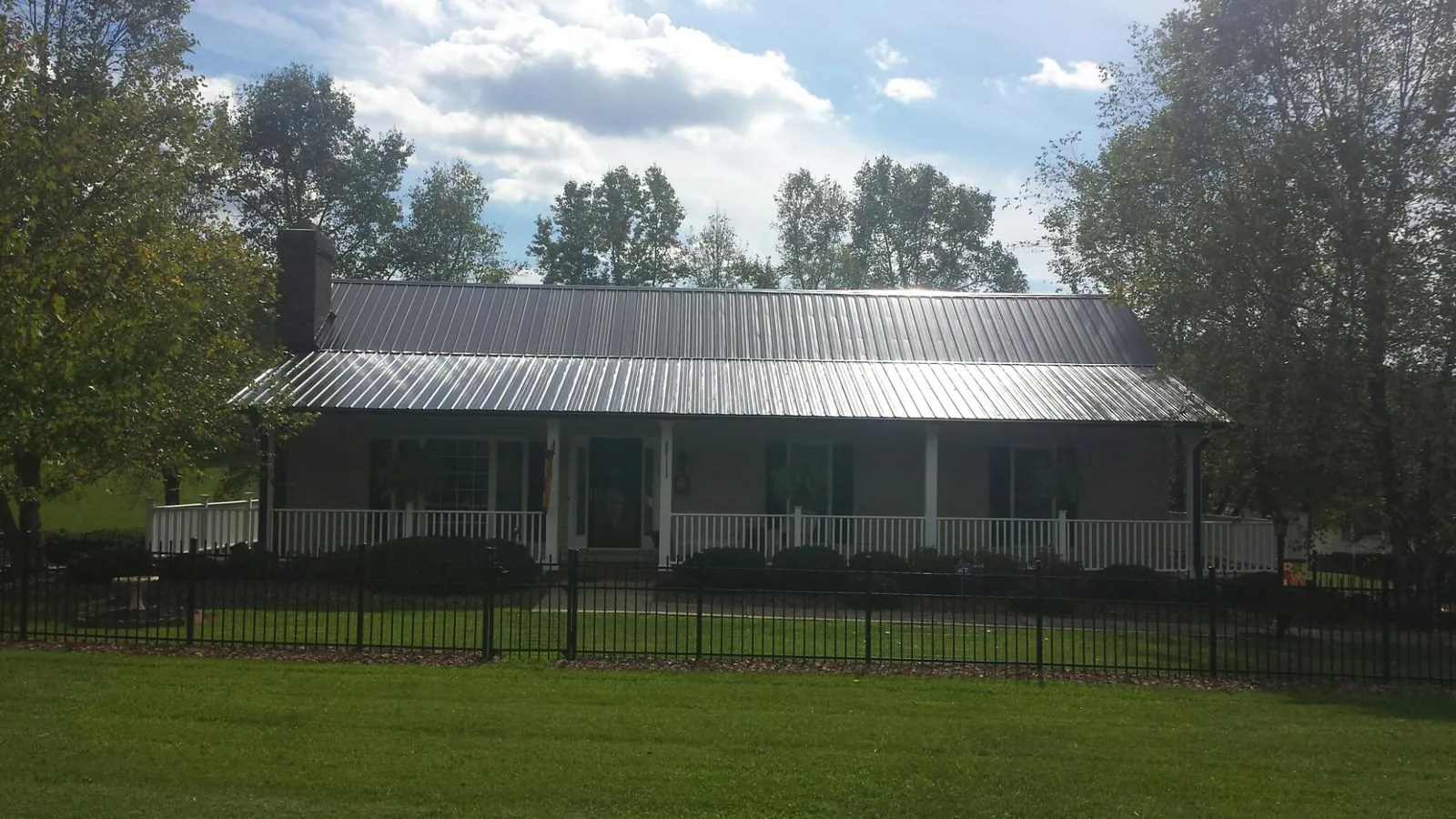 Gray metal roof on a brick ranch with a full width front porch — Gutter Guard Installation work by our crew in Franklin Furnace