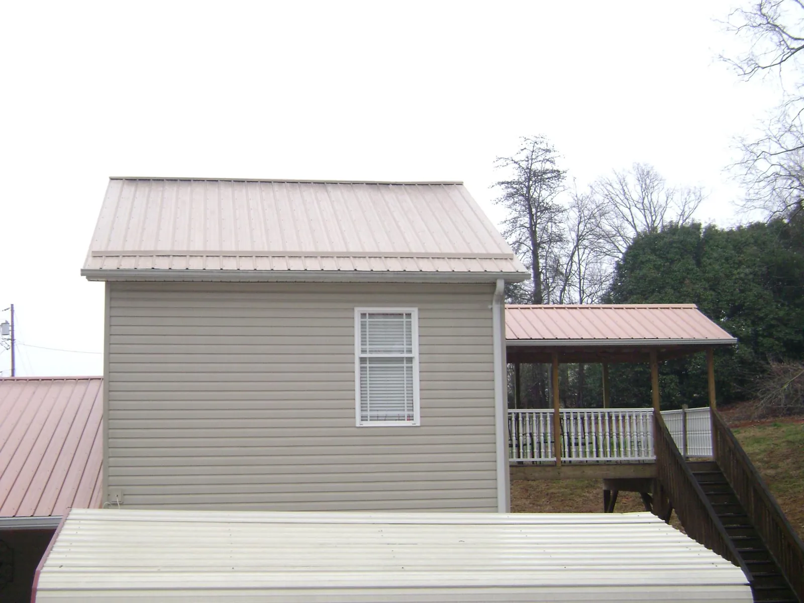 Tan metal roofs on a two story addition and attached porch, from a Roof Replacement job in Franklin Furnace