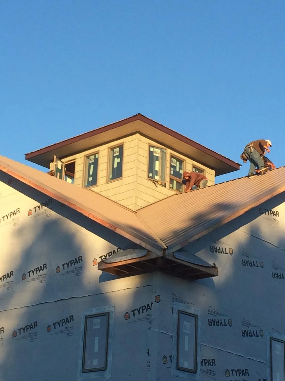 Roofers working around a rooftop cupola on a new metal roof at sunset — Roof Waterproofing in Franklin Furnace by Roofing Brothers